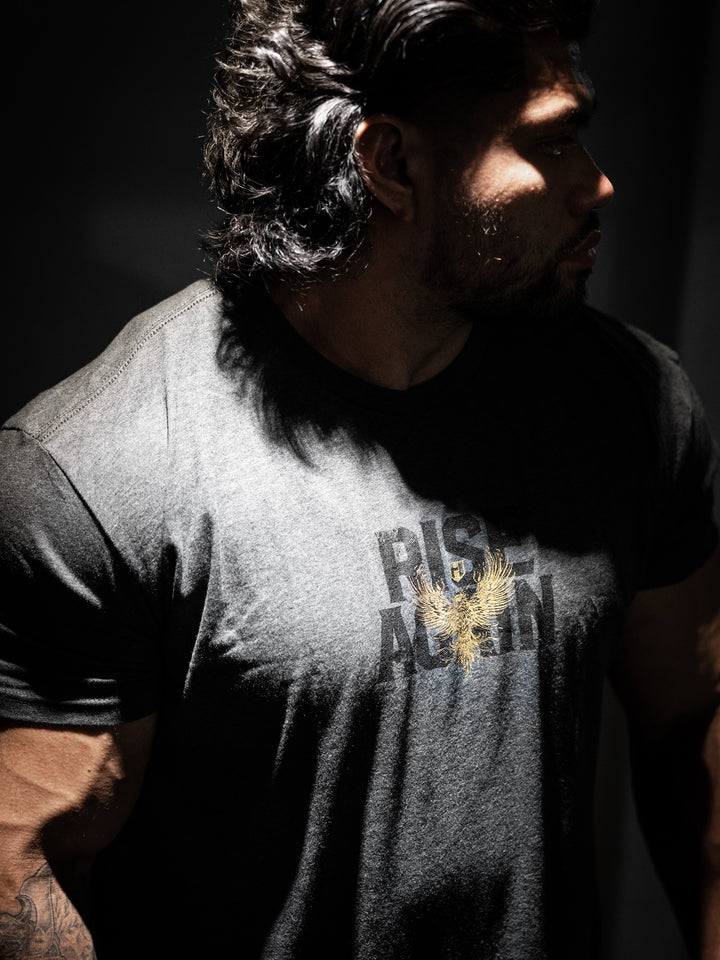 Man wearing a t-shirt with 'Rise Again' printed on it, standing in a dark setting#color_charcoal
