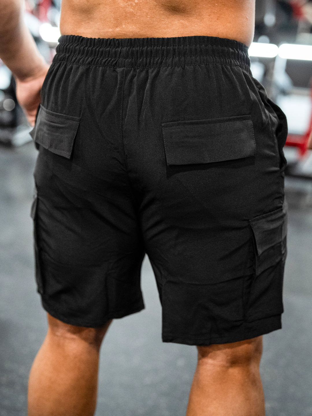 Bodybuilder wearing Shield Cargo Shorts#color_black