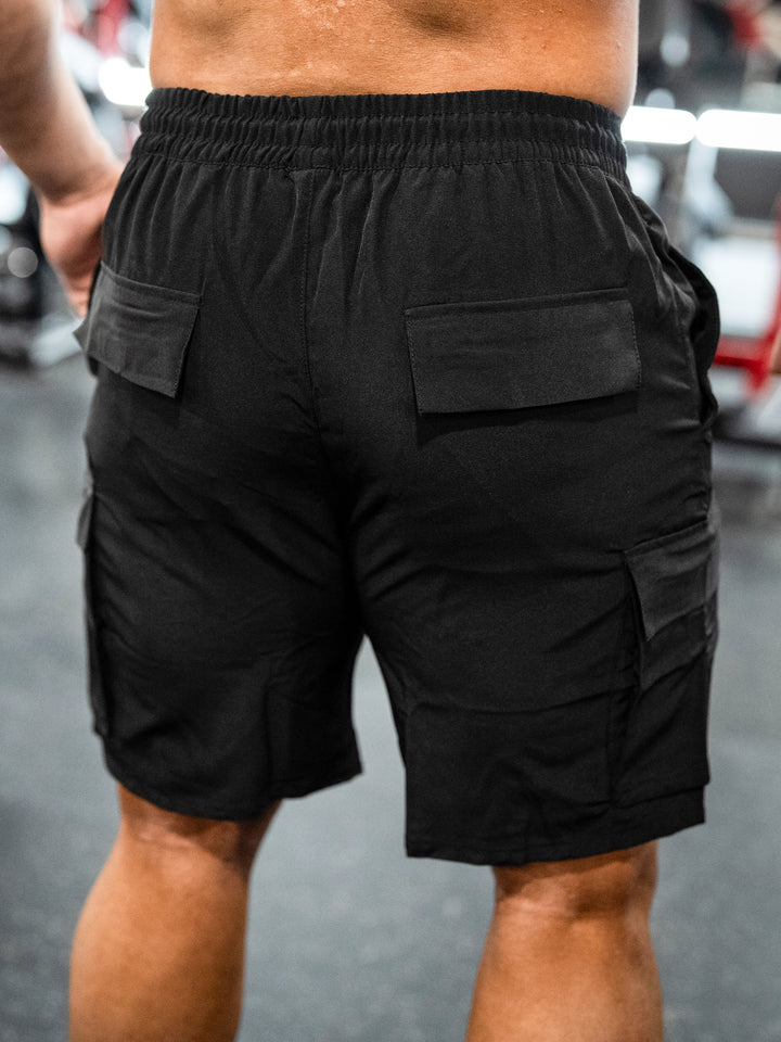 Bodybuilder wearing Shield Cargo Shorts#color_black