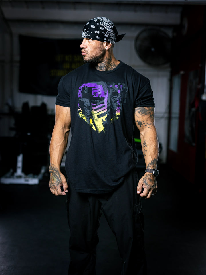 Bodybuilder Ben Chow wearing a black t-shirt with a graphic design and a cap, standing in a gym.#color_black-african-sunrise