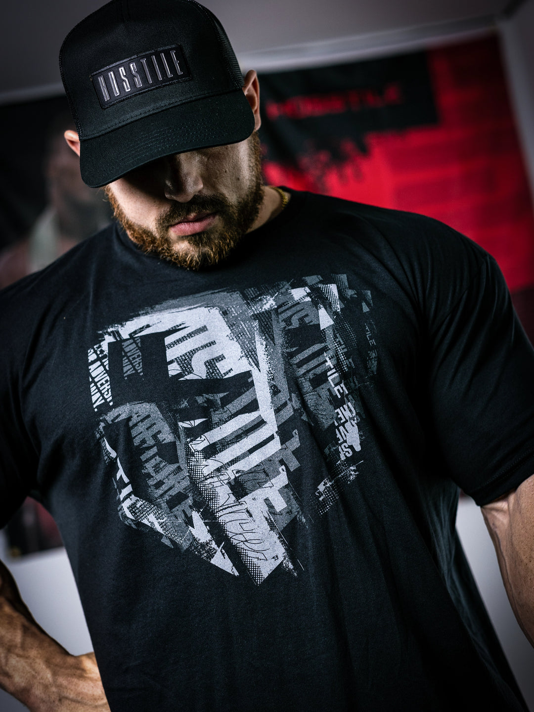 Martin Fitzwater wearing a black t-shirt with a graphic design and a cap, standing in a gym.#color_black-grey