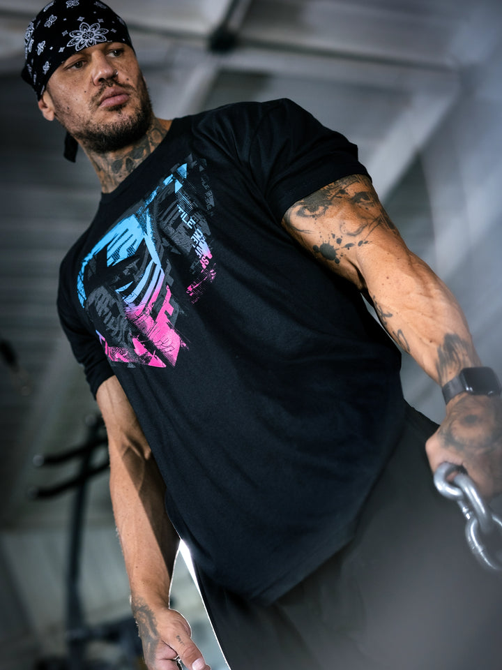 Bodybuilder Ben Chow wearing a black t-shirt with a graphic design and a cap, standing in a gym.#color_black-miami-vice