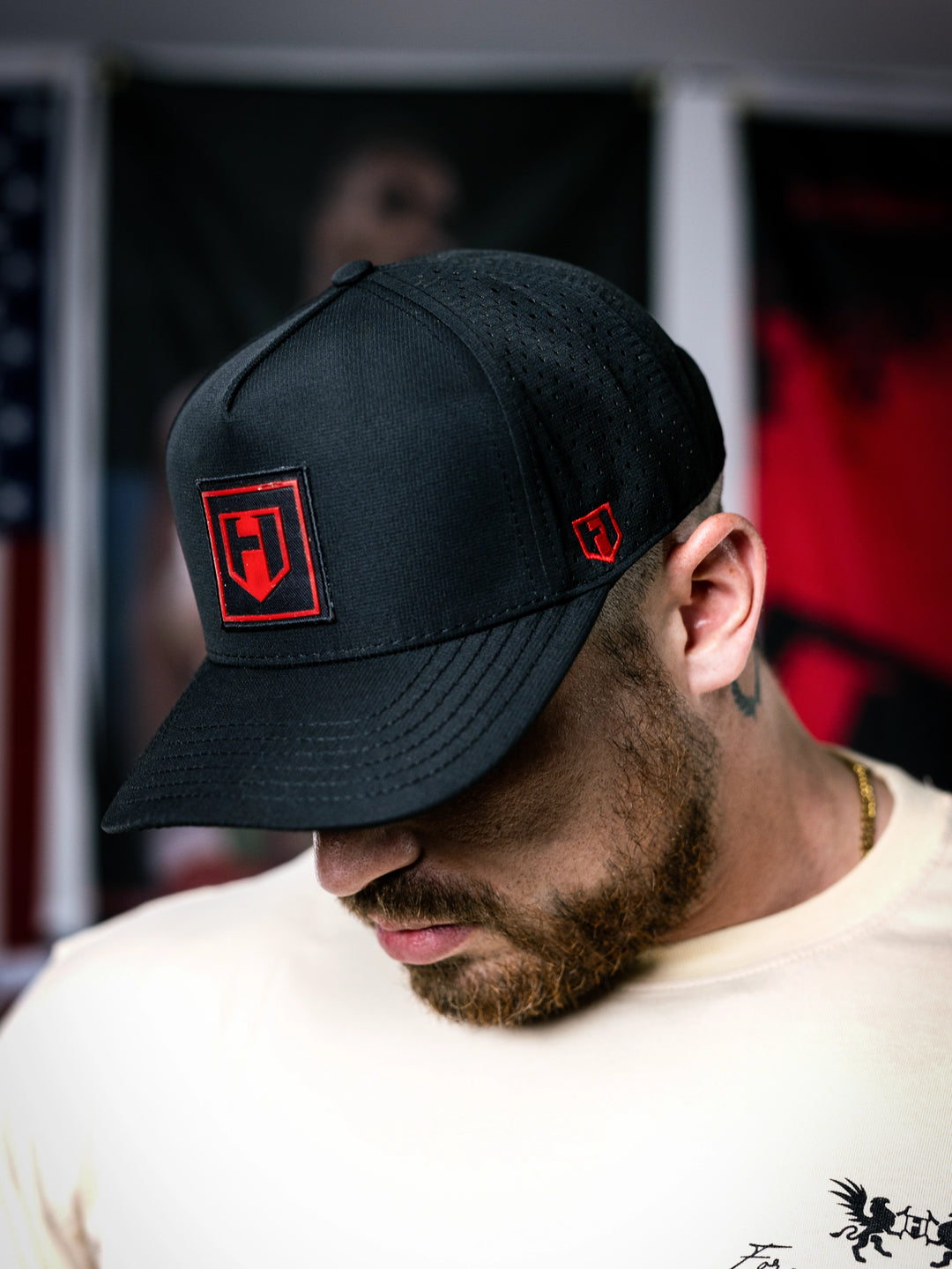Man wearing a black cap with red logo in a blurred indoor setting#color_black