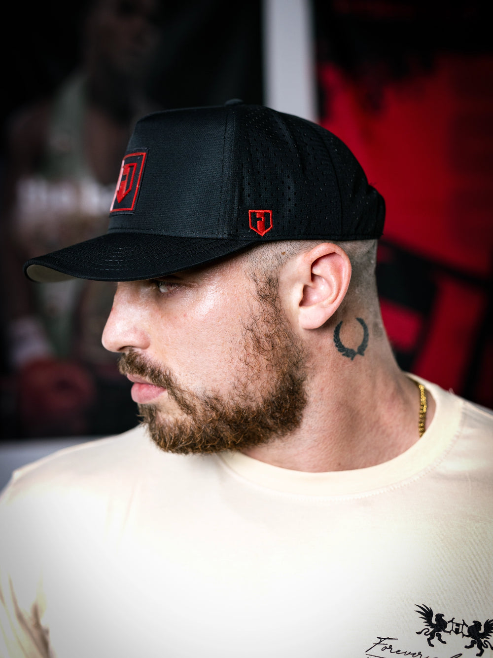 Man wearing a black cap with a red logo, looking to the side.#color_black