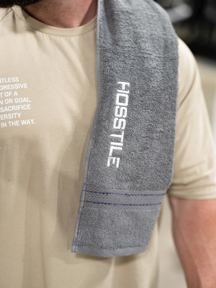 Bodybuilder holding Hosstile gym towel#color_gunship-grey