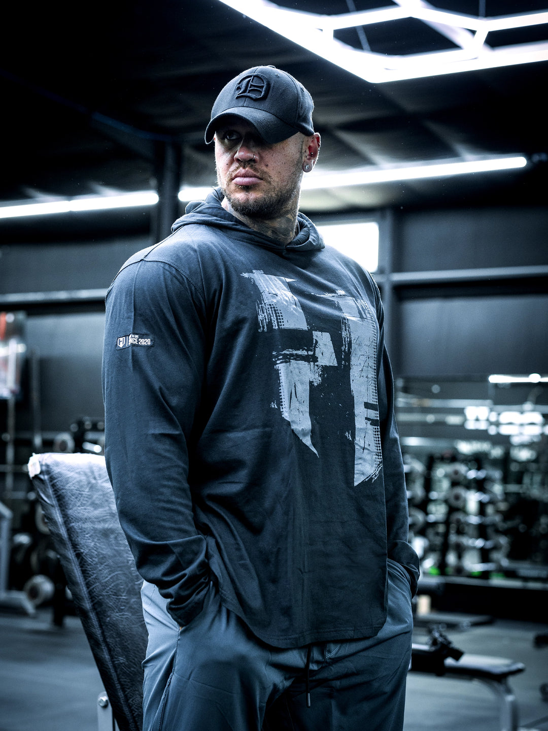 Bodybuilder Ben Chow wearing a black hoodie and cap in a gym setting#color_black