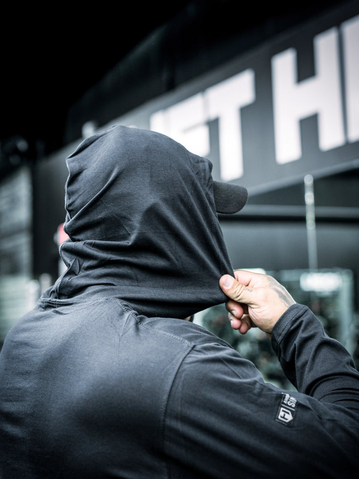 Bodybuilder ben Chow wearing a black hoodie and cap in a gym setting#color_black