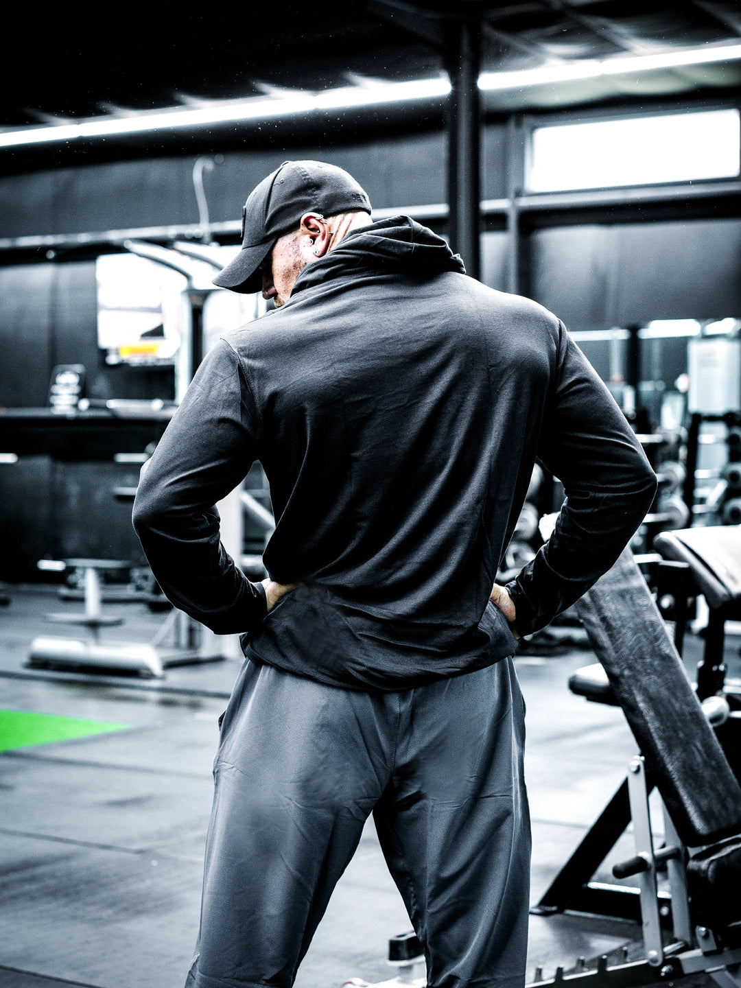 Bodybuilder Ben Chow wearing a black hoodie and cap in a gym setting#color_black