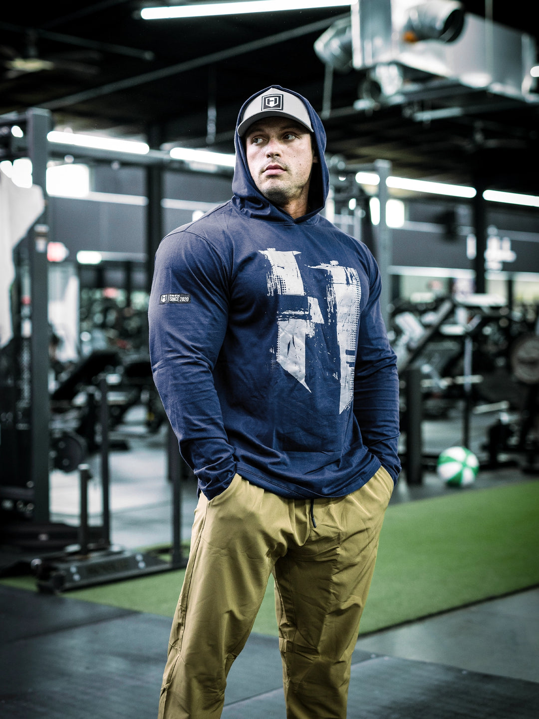 IFBB Pro Bodybuilder Martin Fitzwater wearing a navy hoodie and cap in a gym setting#color_navy