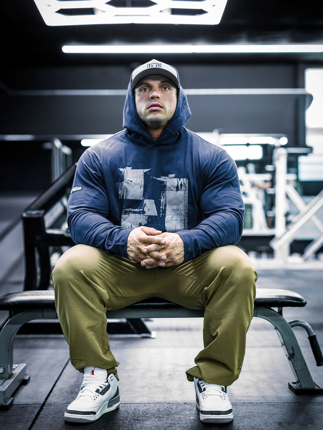 IFBB Pro Bodybuilder Martin Fitzwater wearing a navy hoodie and cap in a gym setting#color_navy