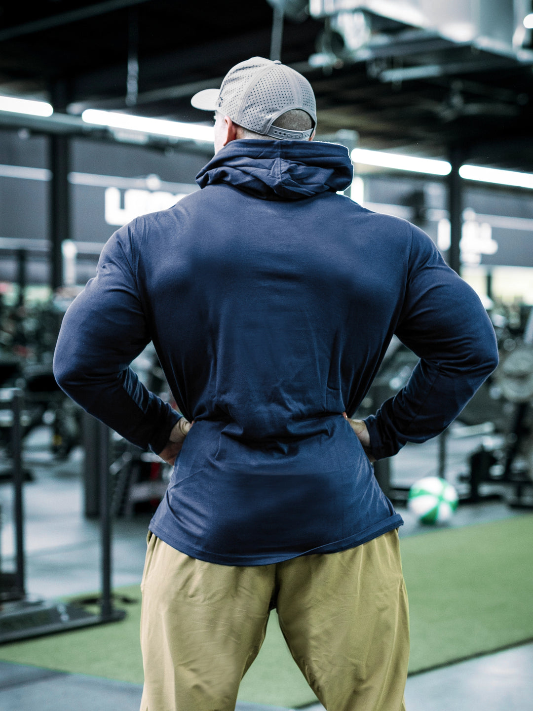 IFBB Pro Bodybuilder Martin Fitzwater wearing a navy hoodie and cap in a gym setting#color_navy