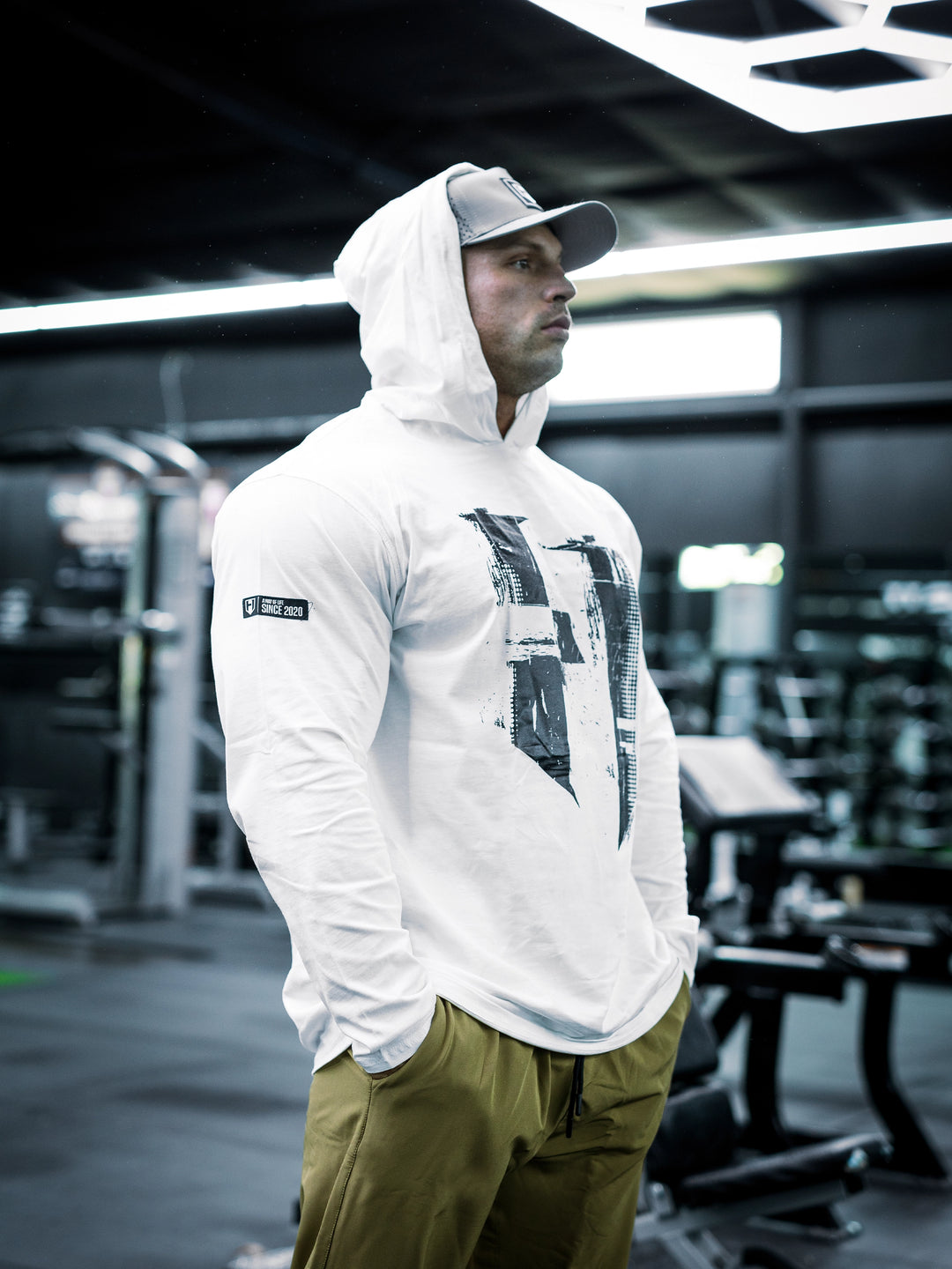 IFBB Pro Bodybuilder Martin Fitzwater wearing a white hoodie and cap in a gym setting#color_white