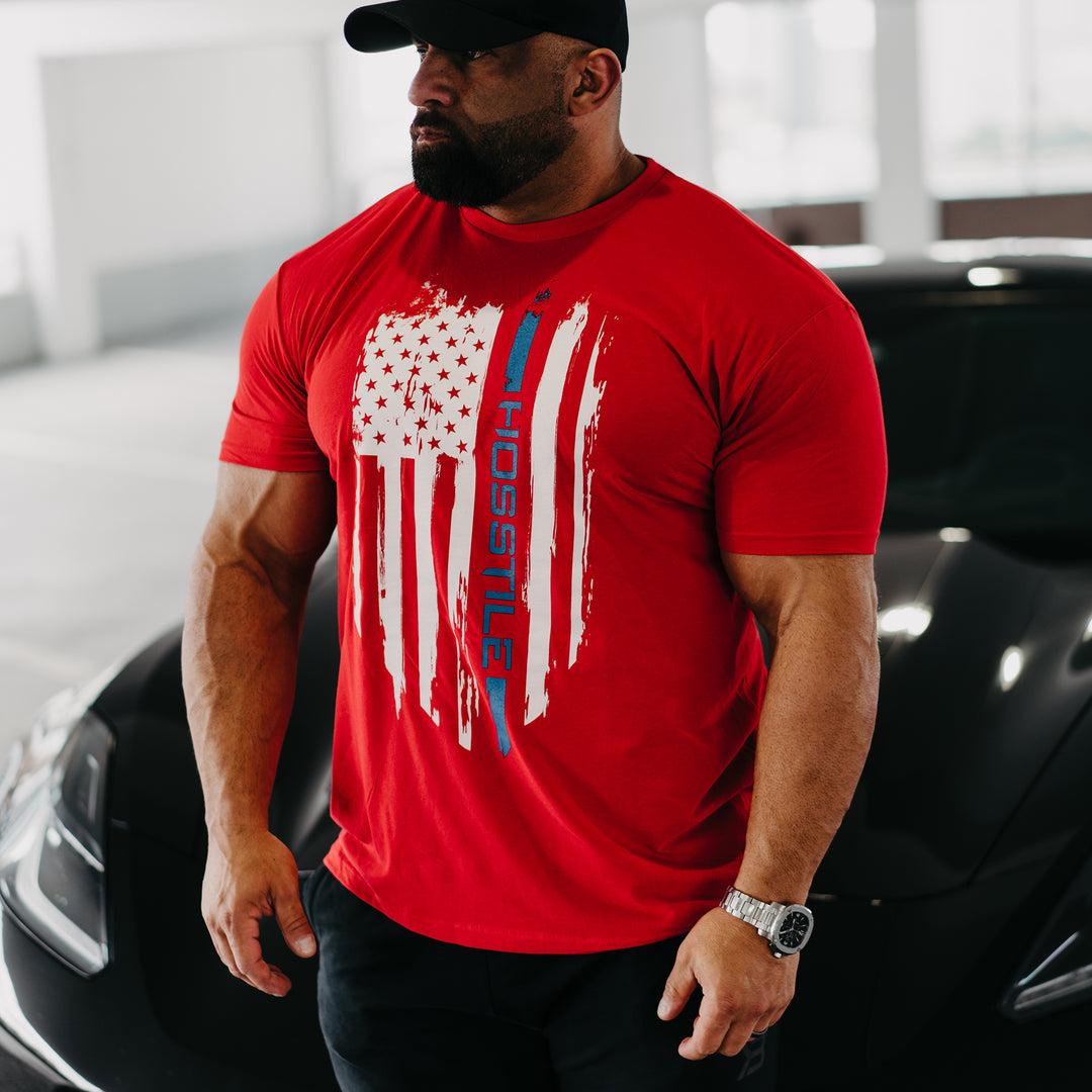 Bodybuilder Fouad Abiad standing to the side of corvette wearing Patriot t-shirt